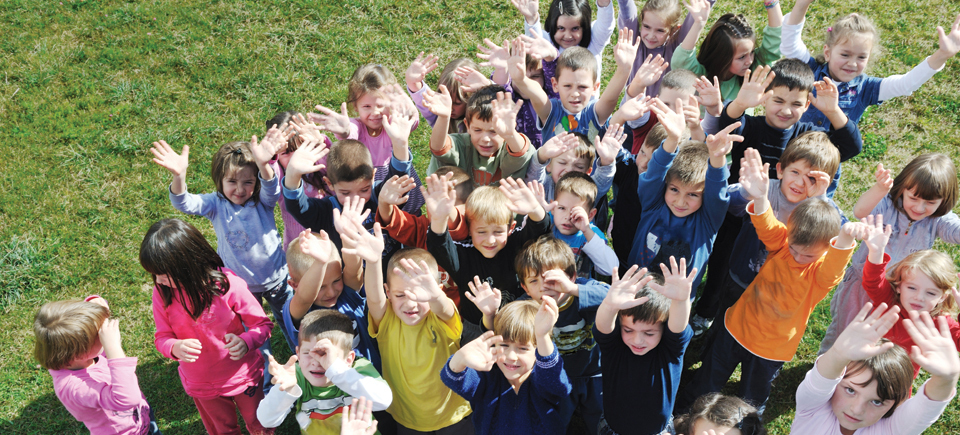 A crowd of children looking way up at the camera.