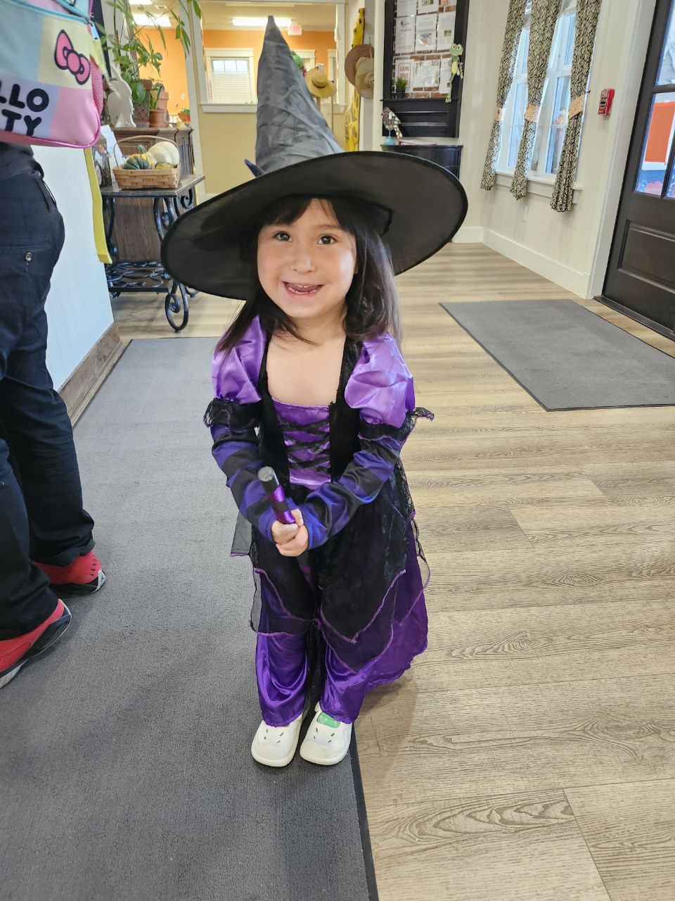 A girl in a purple witch costume wearing a black pointed hat.